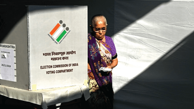 A voter leaves the polling booth after casting her ballot in state assembly elections in Mumbai, India, on Nov. 20, 2024. (Photo by Indranil Mukherjee/AFP via Getty Images)
