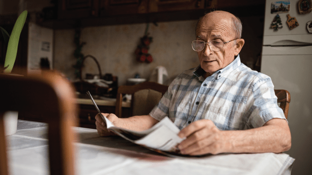 Senior man reading daily newspapers at home