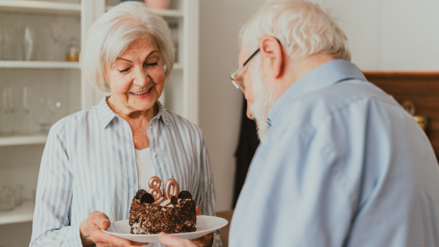 Stock photo of a man and woman celebrating an 80th birthday with cake.