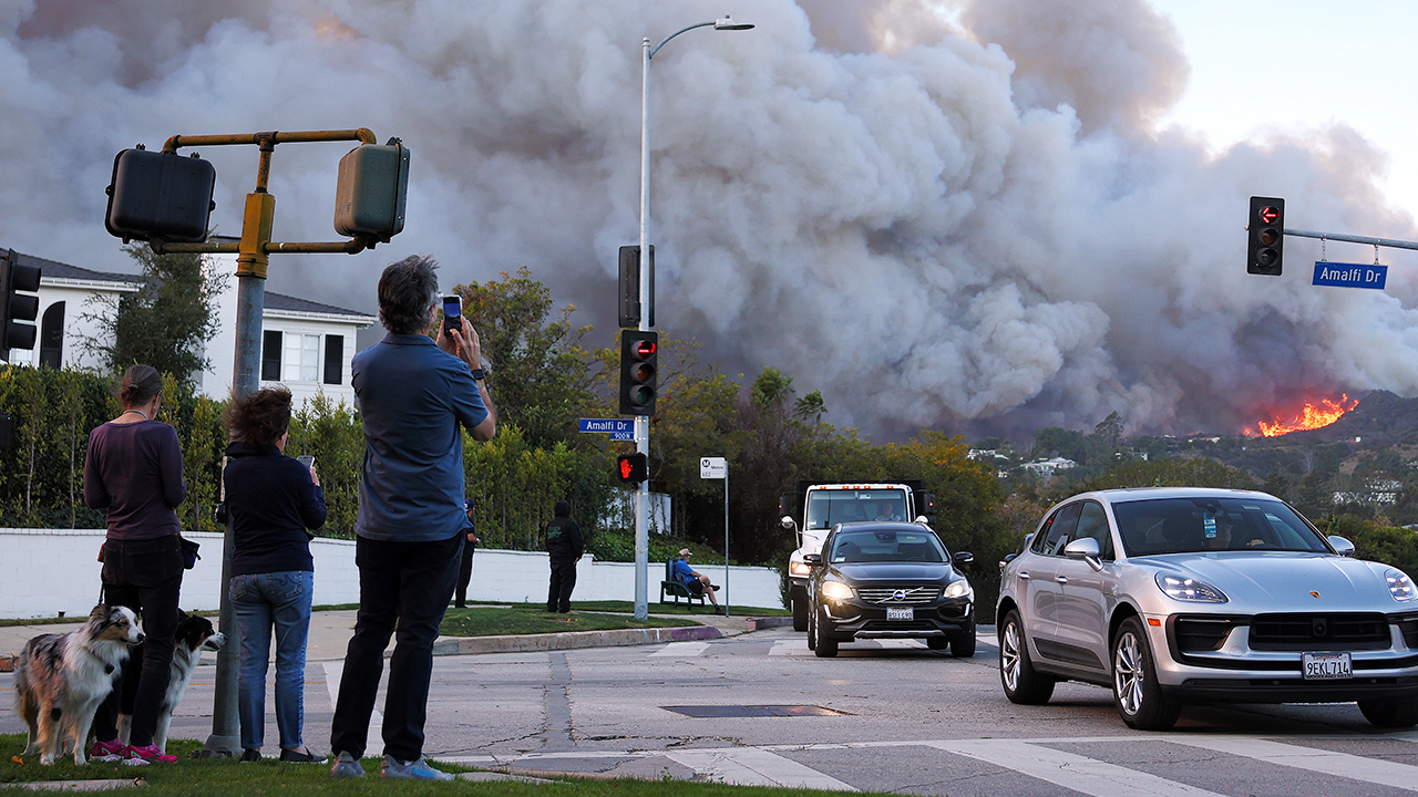 People watch others leaving the Palisades fire on 7 January 2025 in Pacific Palisades, California. (Mario Tama/Getty Images)