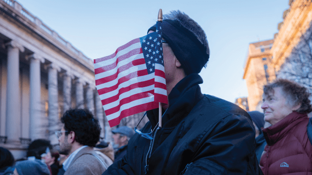 A demonstrator stands with an American flag planted in his coat during a protest in front of the U.S. Treasury Department in Washington, D.C., on Feb. 4, 2025. (Hossein Fatemi/Middle East Images/AFP via Getty Images)