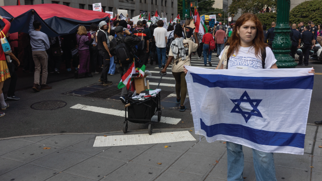 A counterprotester holding an Israeli flag passes a group of pro-Palestinian demonstrators marching in Lower Manhattan, New York City, in October 2024. (Andrew Lichtenstein/Corbis via Getty Images)