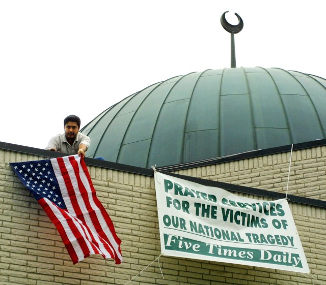A man hangs an American flag from the roof of the Mosque Foundation in the Chicago suburb of Bridgeview, Illinois, on Sept. 13, 2001. (John Zich/AFP via Getty Images)
