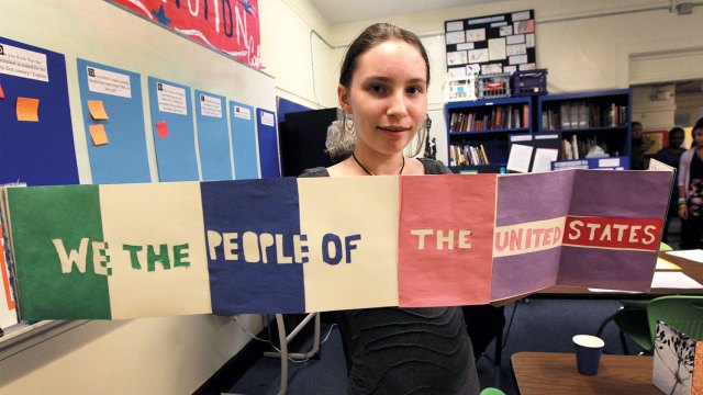 An eighth grader at Meridian Academy in Boston holds her humanities class project using the preamble to the Constitution. (Barry Chin/The Boston Globe via Getty Images)